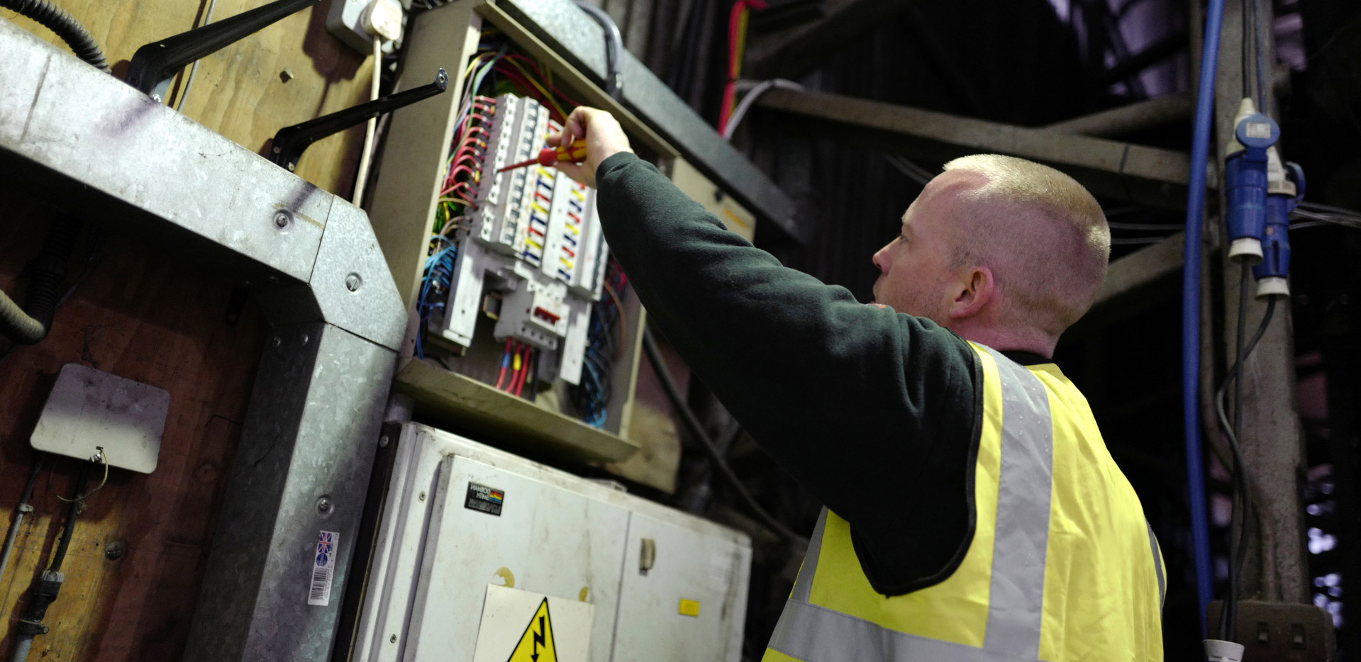 Man in high vis screwing a fuse box together